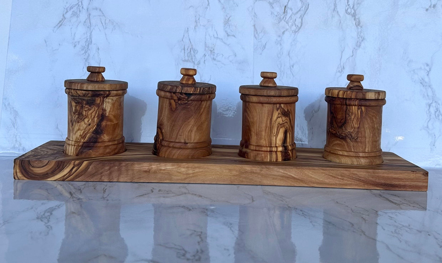 Set of four wooden canisters on a wooden tray against a marble background