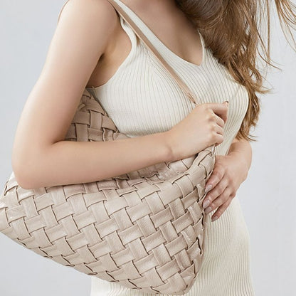 Woman holding a woven beige handbag 