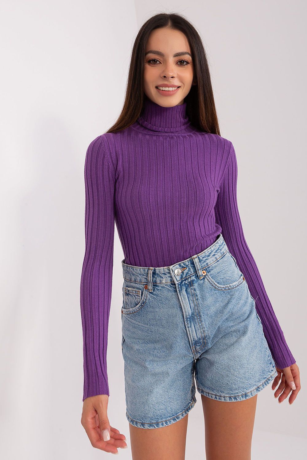 Woman wearing a purple ribbed turtleneck and denim shorts