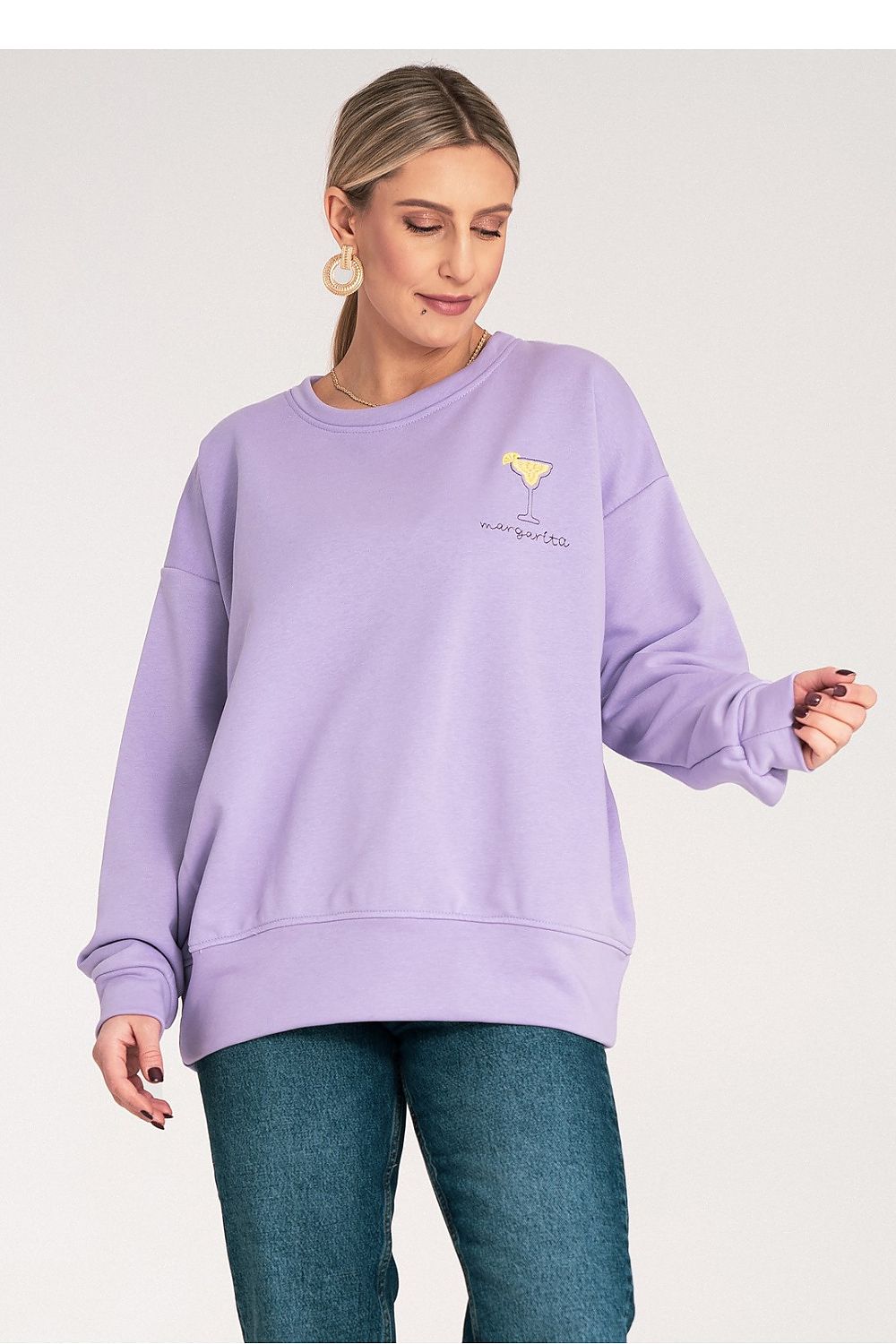 Woman wearing a light purple sweatshirt with a small yellow logo 
