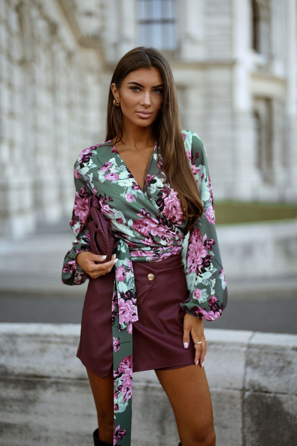 Woman wearing a floral silk blouse  and a burgundy leather skirt 