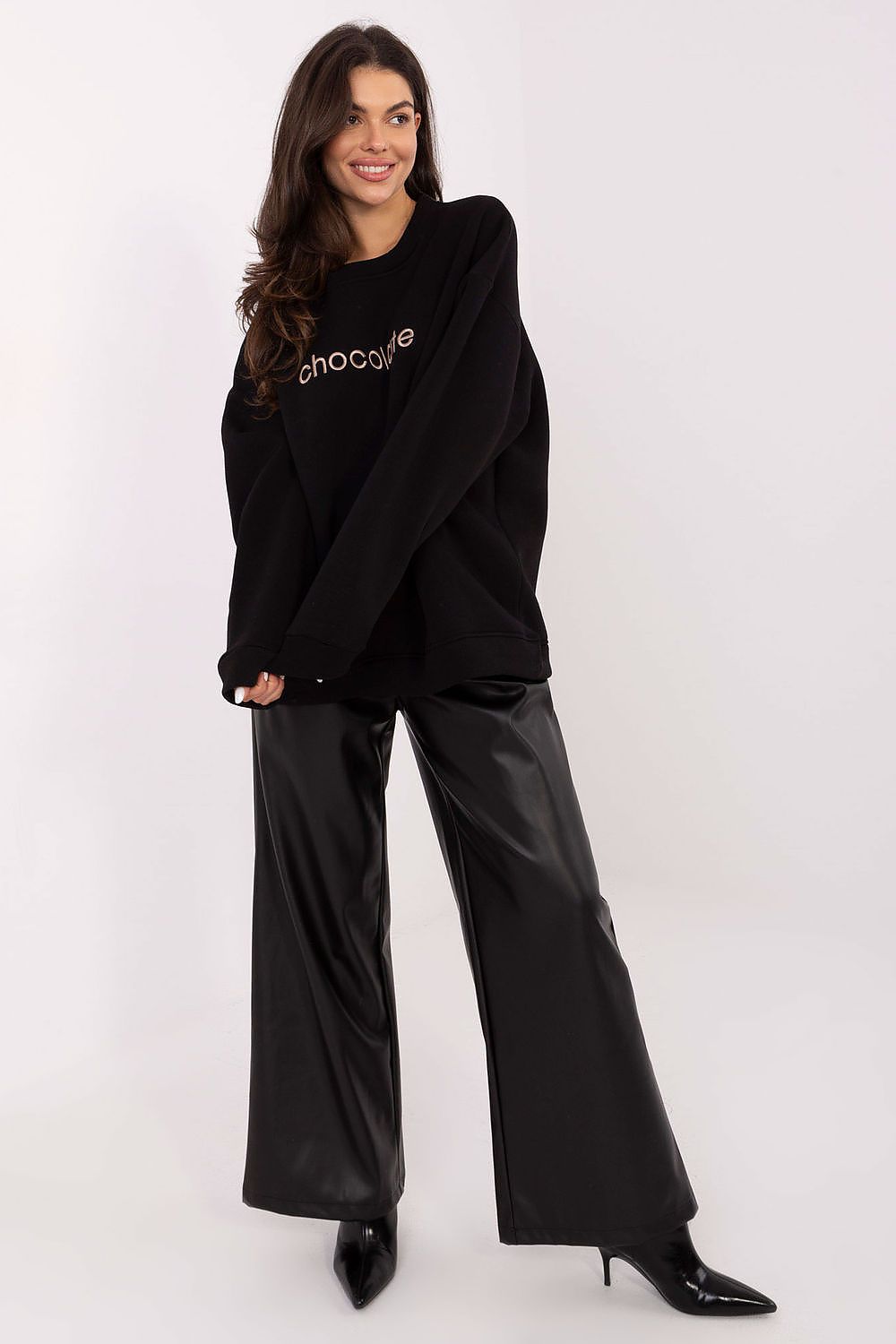 Woman wearing a black oversized sweatshirt with text and black pants 