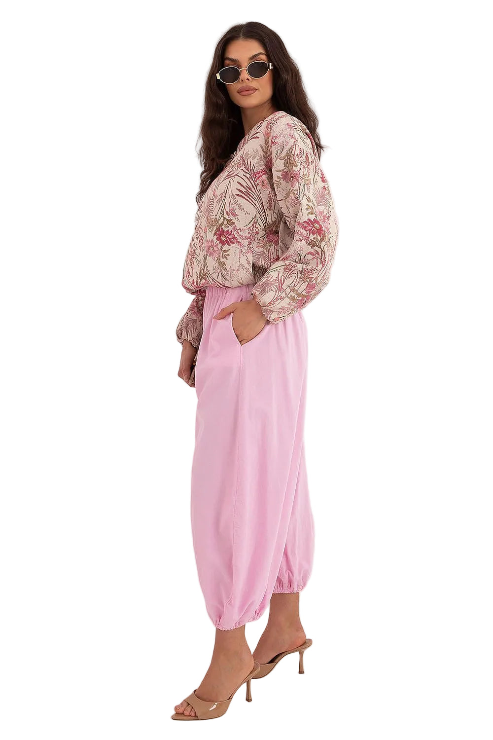 Full-body side view of a model styling a pink floral patterned silky shirt with relaxed pink pants.