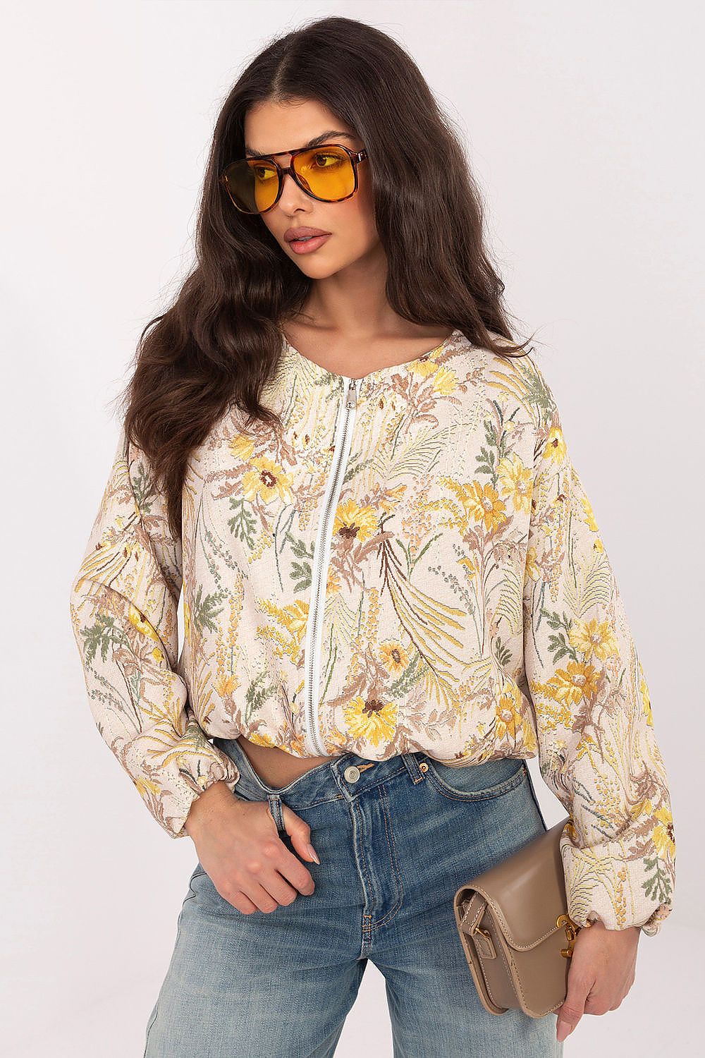 Front view of a model in a beige and yellow floral print button-up shirt paired with blue jeans.