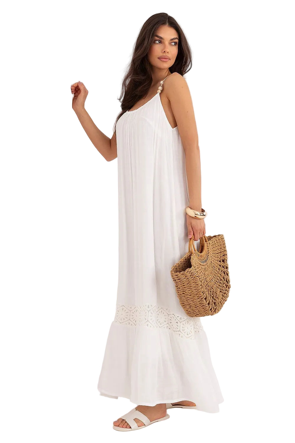 Side-angle view of a woman wearing a white cotton-blend boho dress while carrying a woven straw beach bag.