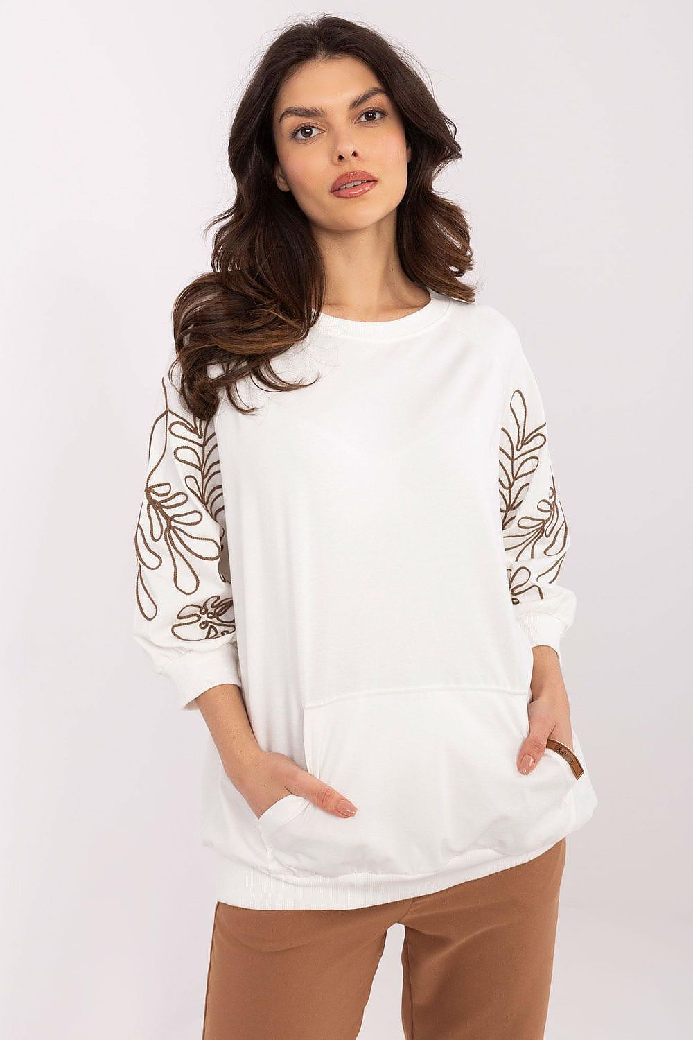 Oversized white women's sweatshirt with intricate floral embroidery on the sleeves, featuring front pockets and a crew neck.