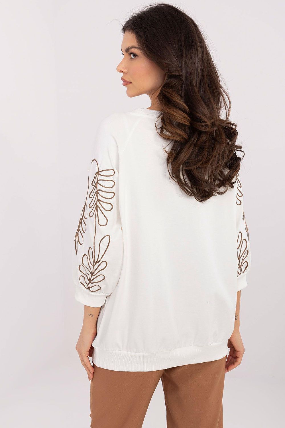 Back view of a white oversized sweatshirt for women, showcasing the floral embroidery trailing down the sleeves.