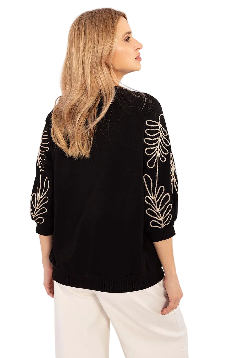 Back view of a woman wearing a black oversized loungewear sweatshirt with white embroidered details on the sleeves.
