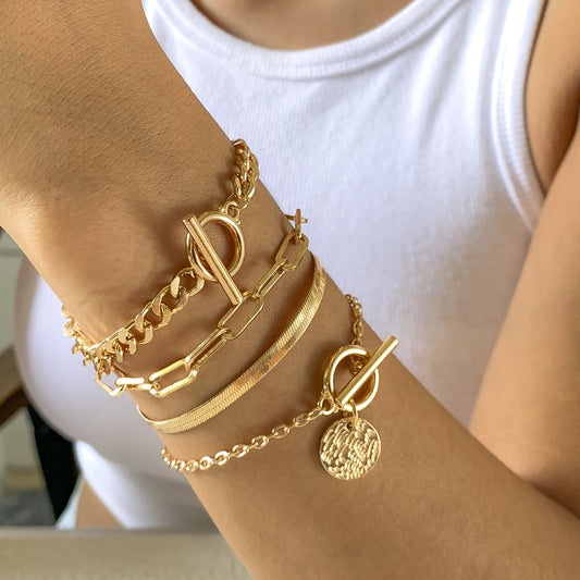 Gold 4-bracelet set with chain and toggle clasps stacked on wrist
