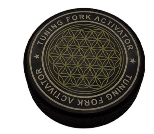 Round black and gold product labeled 'Tuning Fork Activator' with a geometric design 