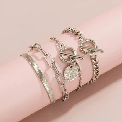 Silver bracelets on a pink arm against a pink background