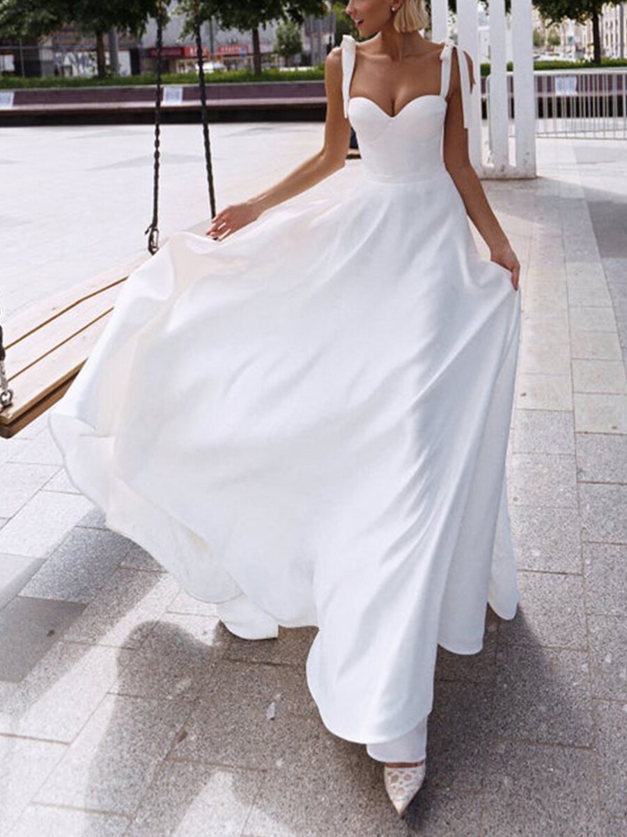 Full length white modern bridal gown with fluid train and high slit in outdoor setting


