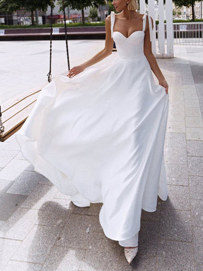 Full length white modern bridal gown with fluid train and high slit in outdoor setting

