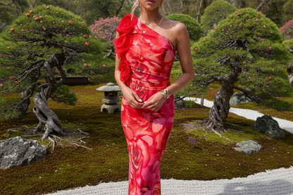 Woman wearing a vibrant red and pink one-shoulder dress with floral details 