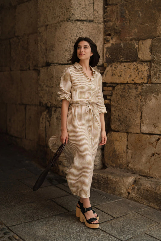 Woman wearing long linen shirt dress with side slits and belt.