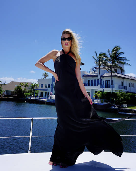 Woman in a black dress standing on a boat with a scenic background