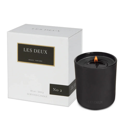 Black candle with 'LES DEUX' branding next to its packaging 